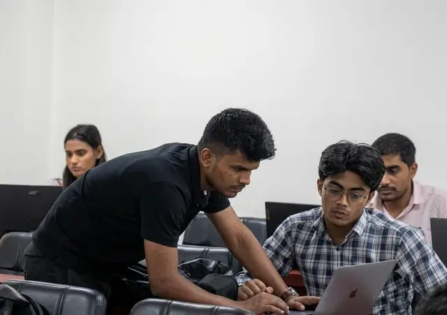 A mentor works with students at their laptops